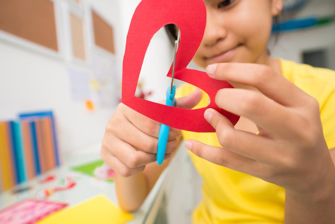 Child cutting paper heart