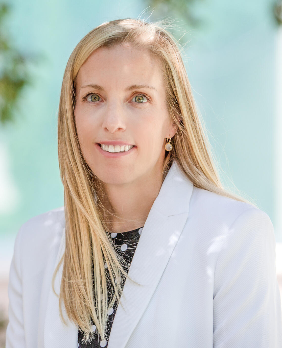 A woman with long blonde hair wearing a white doctor coat