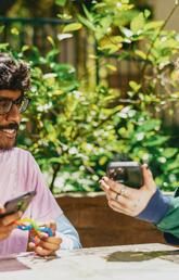 Two autistic friends sitting outside using stim toys and laughing at their phones